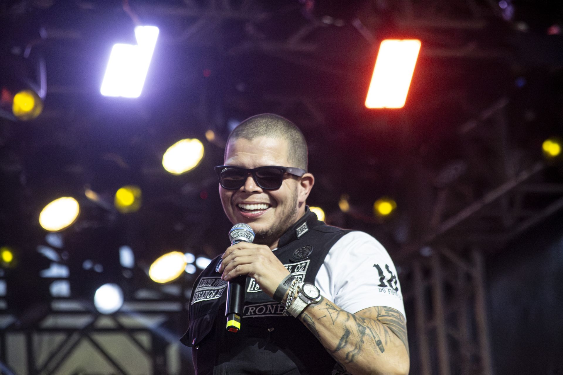 Integrante do Insanos MC sorrindo no palco sob as luzes do show